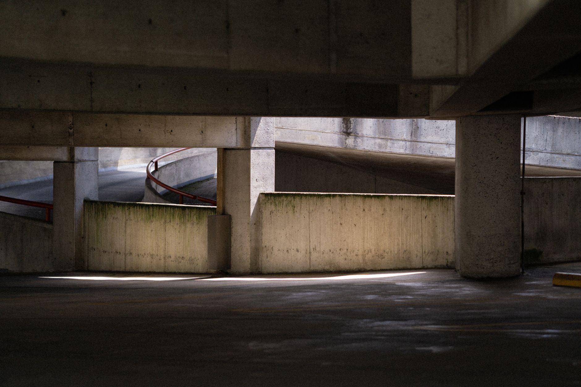 Concrete parking garage with spiral ramp and lighting effects creating shadows.