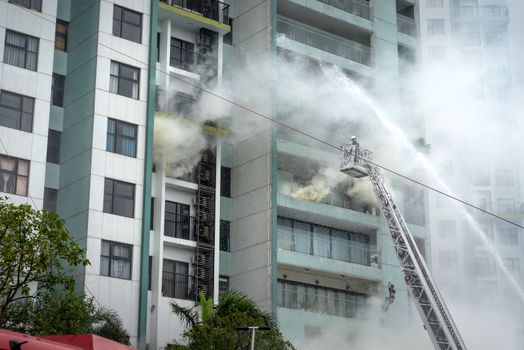 Dramatic scene of firefighters battling a building fire using a ladder and hose.