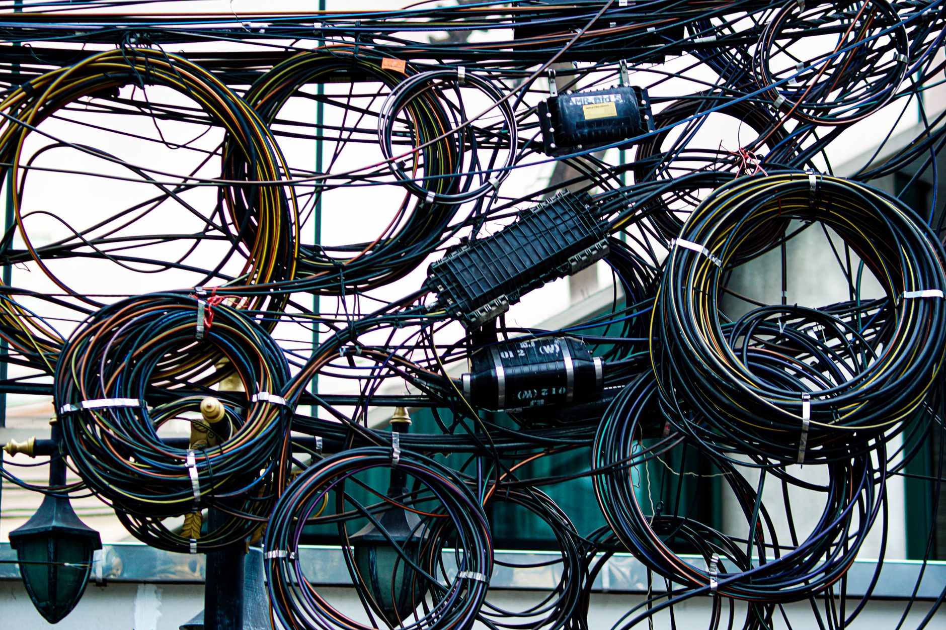 Intricate network of tangled power and communication cables outdoors.