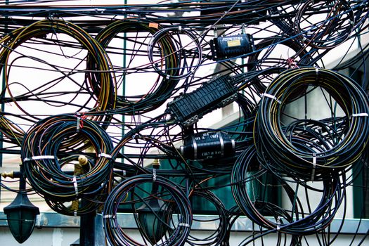 Intricate network of tangled power and communication cables outdoors.