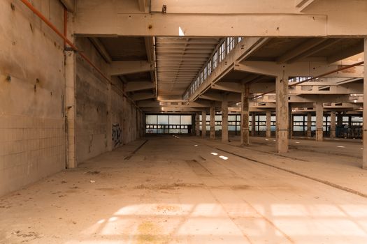 Explore an abandoned industrial warehouse with sunlit interior and empty spaces.