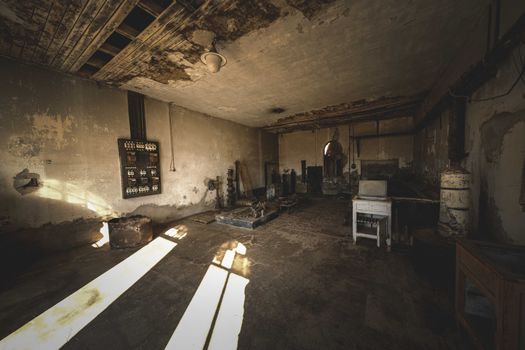 A desolate industrial room with vintage machinery and strong shadows creating a mysterious atmosphere.