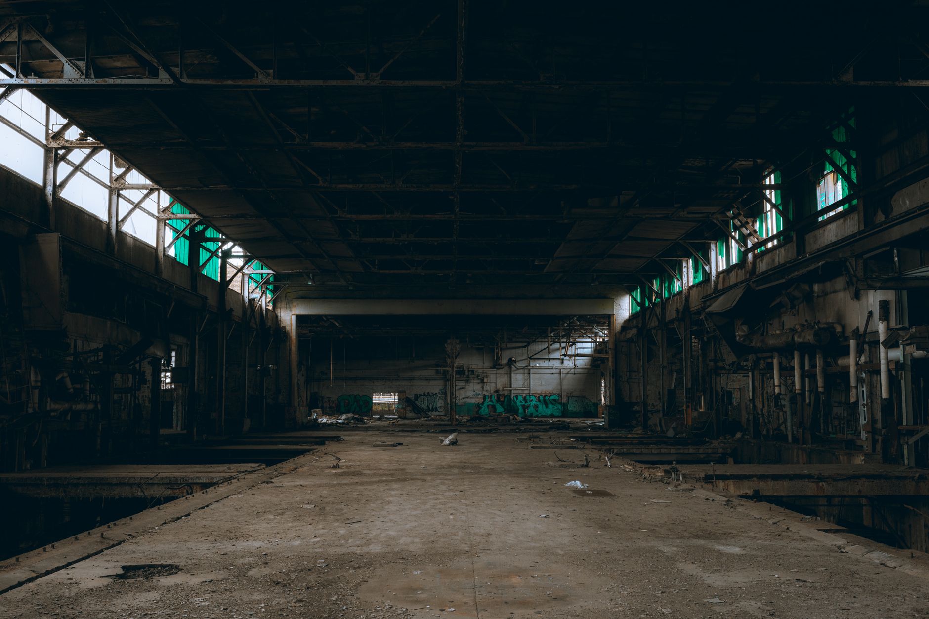 Moody abandoned industrial building interior with graffiti and natural lighting through windows.