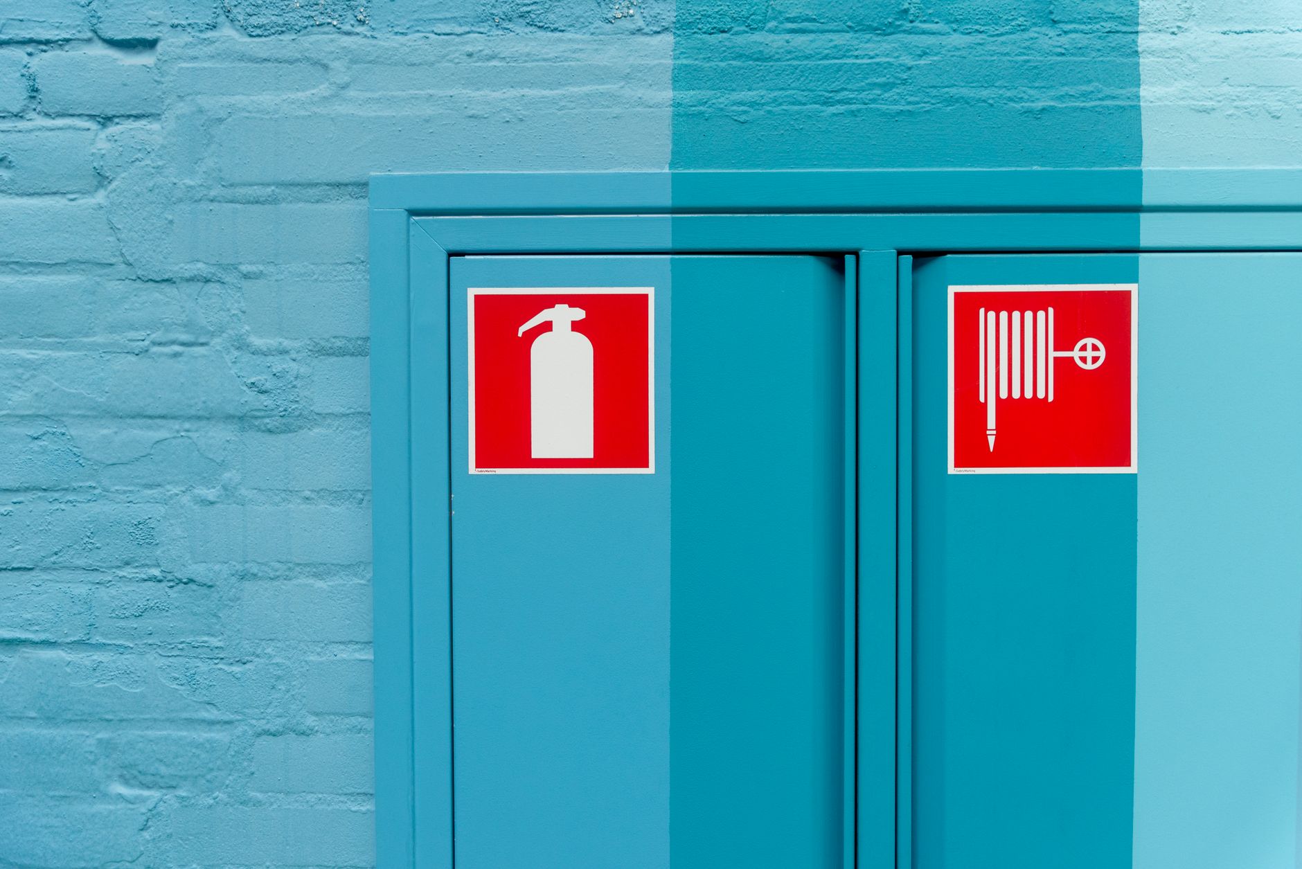 Blue wall featuring prominent fire extinguisher and hose signs for safety.