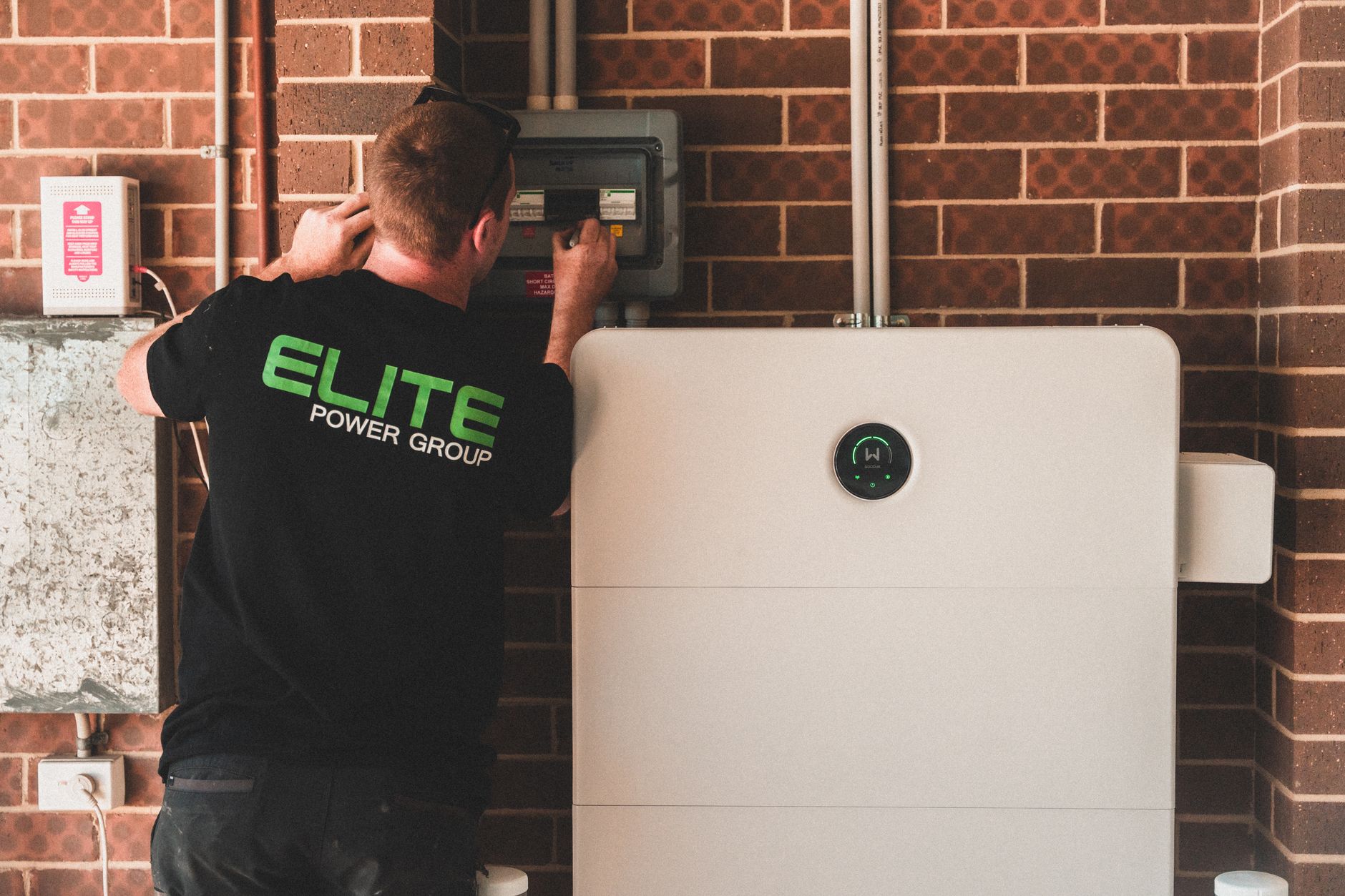 Electrician installing a home energy battery storage unit. Renewable and sustainable energy solution for residential use.