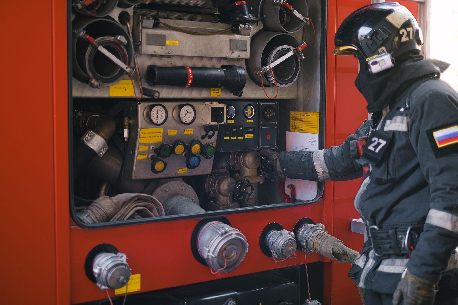Firefighter in uniform adjusts the control panel of a fire truck. Ensuring safety and rescue operations.